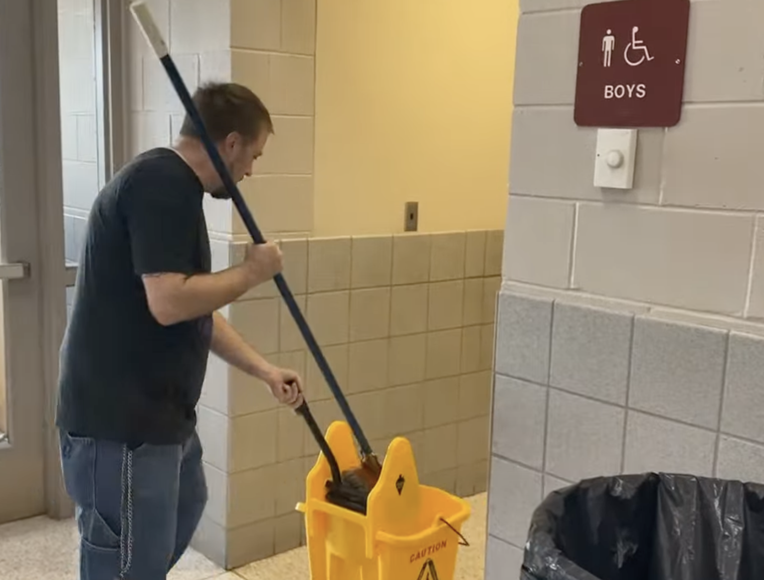  Custodian with bucket about to enter bathroom